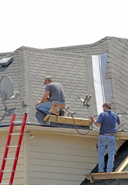 Two men, roofers, lay down a new roof on a home in the neighborhood. (14MP camera)