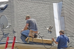 Two men, roofers, lay down a new roof on a home in the neighborhood. (14MP camera)