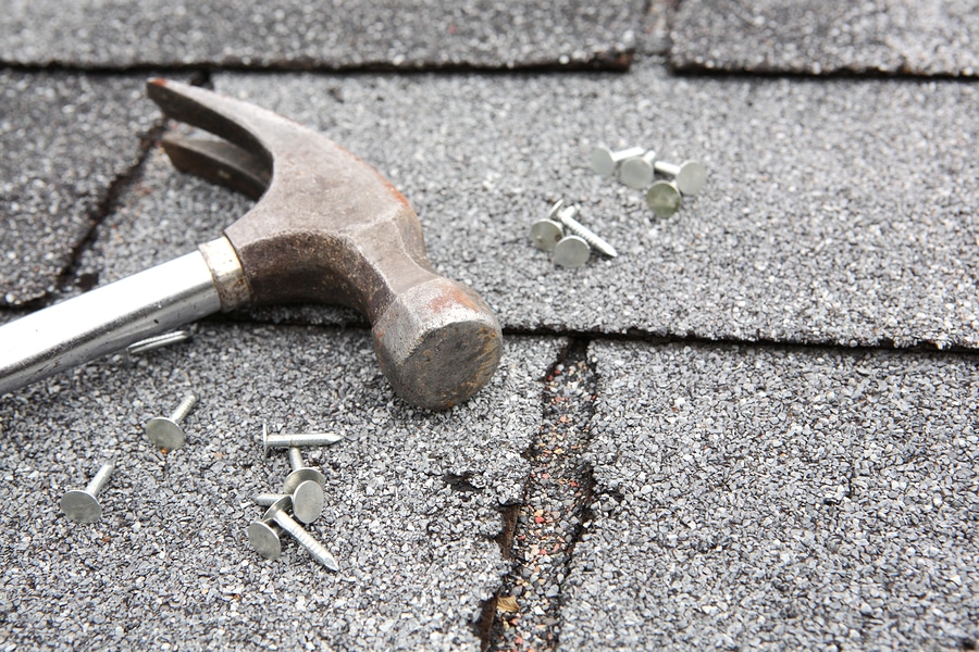 Close-up of hammer and nails on roof shingles